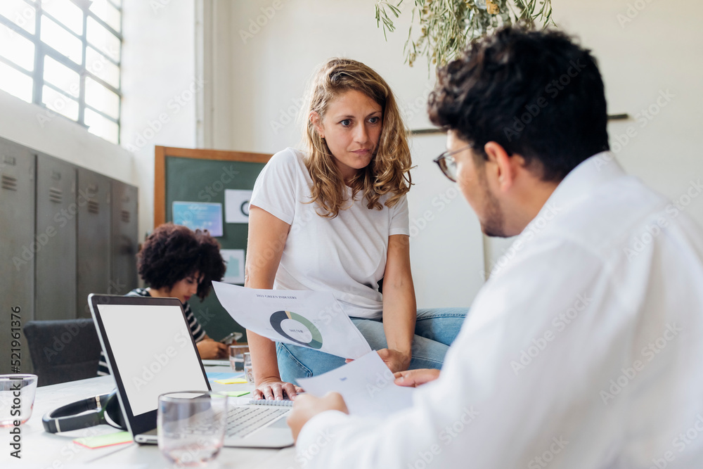 Manager reviewing reports with colleague at work place Manager reviewing reports with colleague at work place