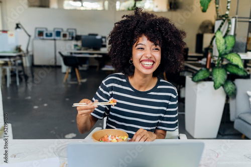 Happy businesswoman having poke bowl in lunch at office photo