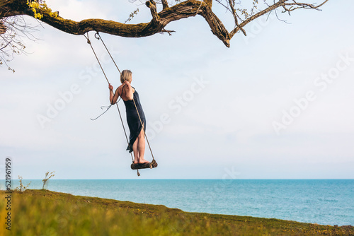 Mature woman balancing on swing in front of sky photo