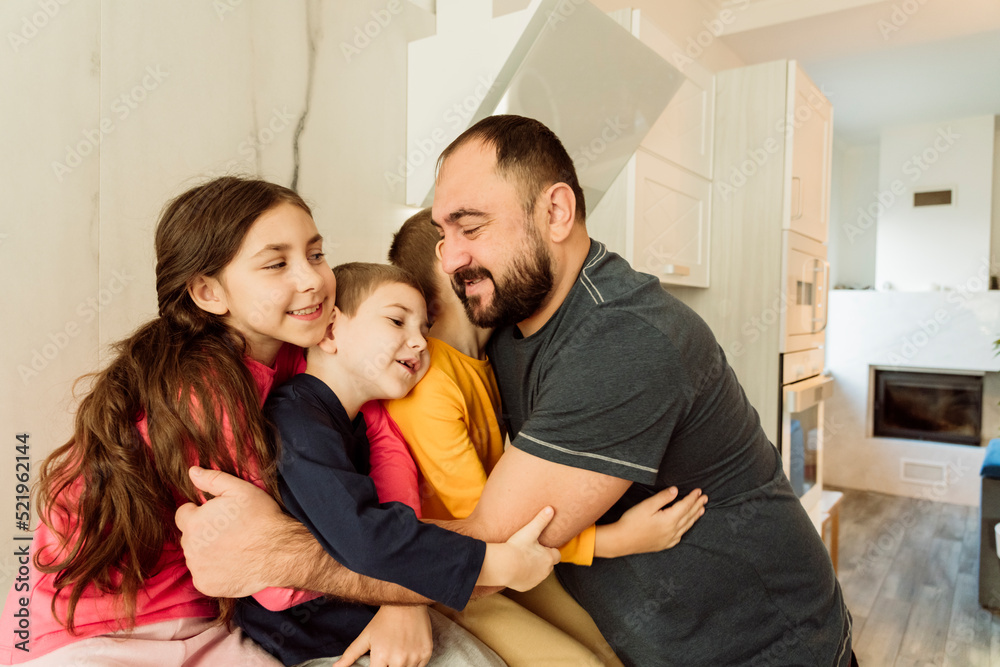 Smiling father embracing children in kitchen