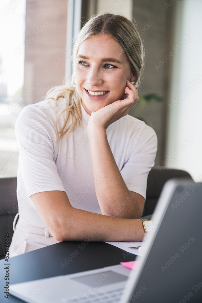 Smiling businesswoman sitting at desk in office Smiling businesswoman sitting at desk in office