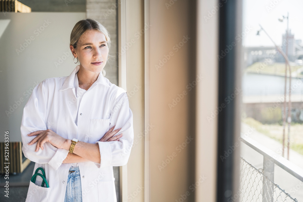 Young doctor with arms crossed leaning on window Young doctor with arms crossed leaning on window