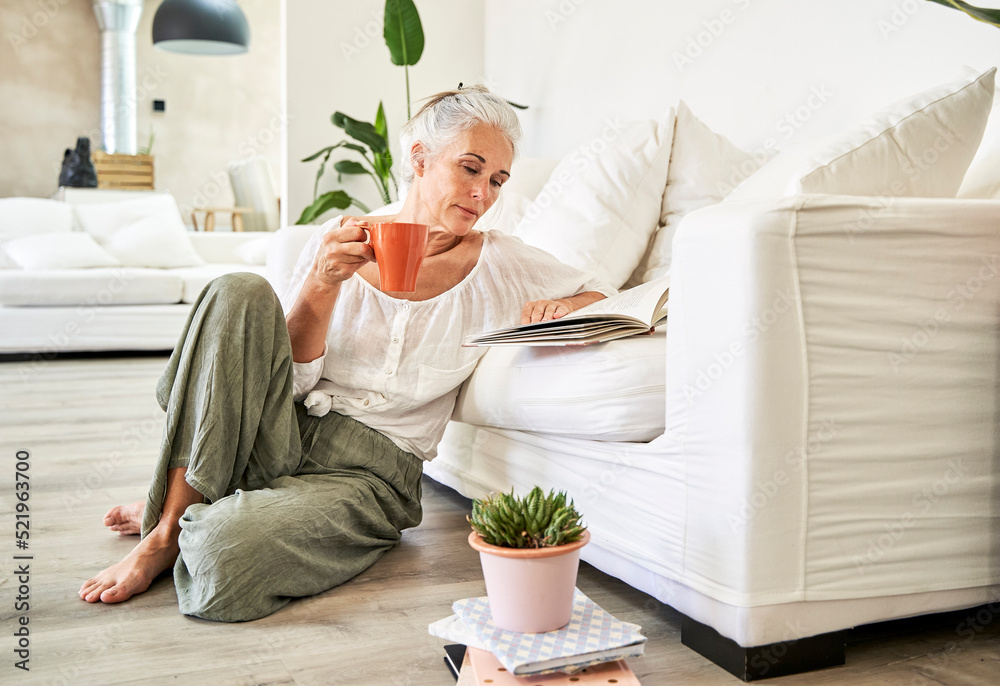 Woman reading book leaning on couch at home Woman reading book leaning on couch at home