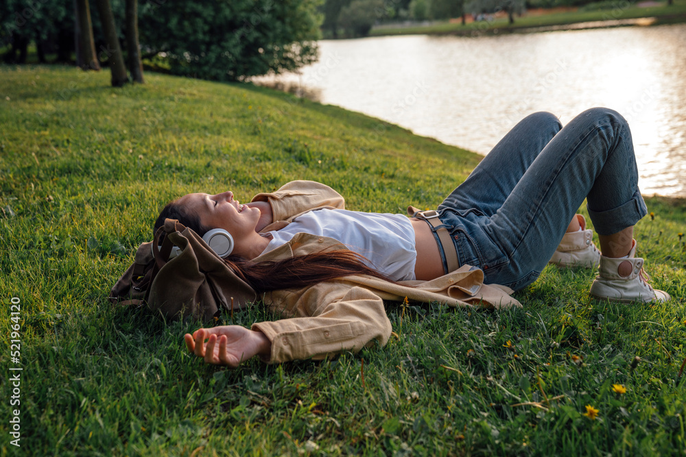 Woman lying down on grass by lake at park Woman lying down on grass by lake at park