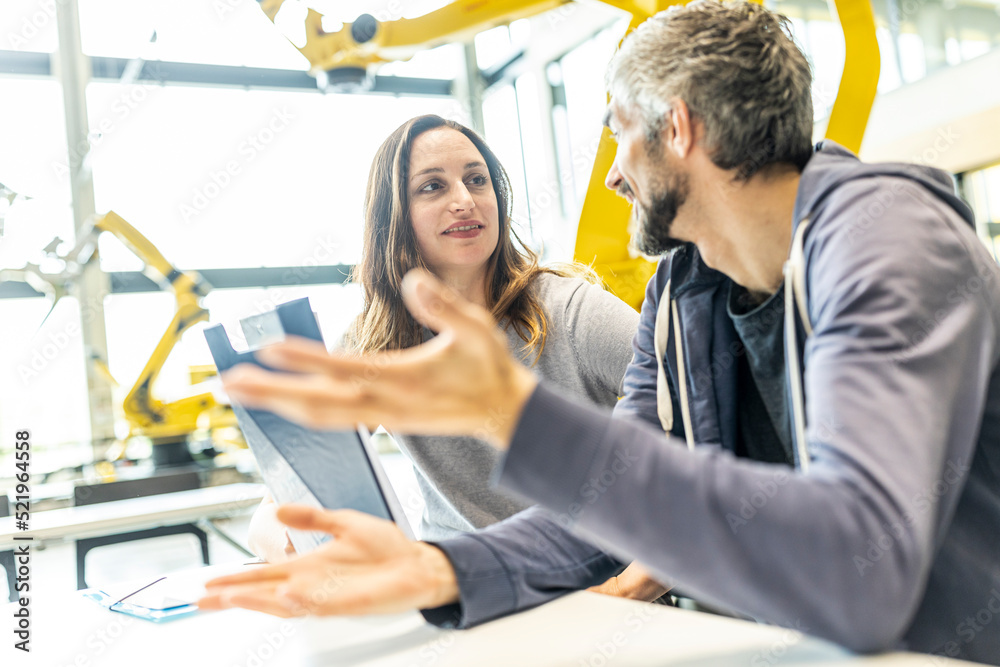 Technician and engineer sitting in factory discussing work solutions Technician and engineer sitting in factory discussing work solutions
