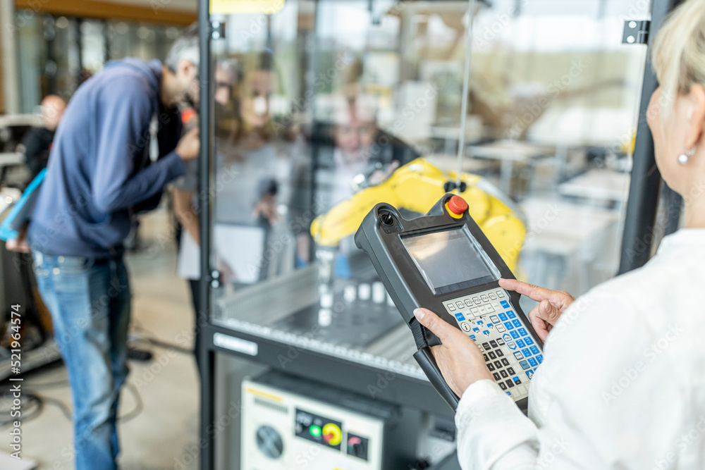 Woman in factory using control of industrial robot Woman in factory using control of industrial robot