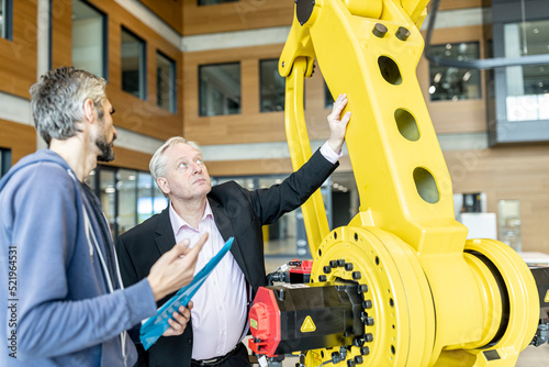 Senior customer getting advise on industrial robot from expert staff photo