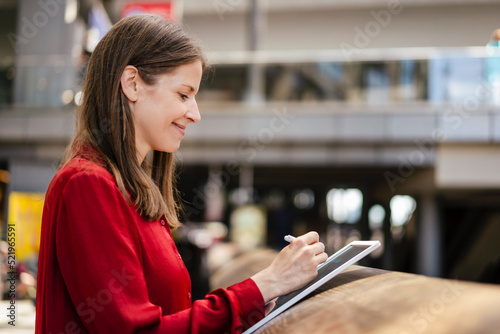 Smiling businesswoman using digitized pen on tablet PC at workplace photo