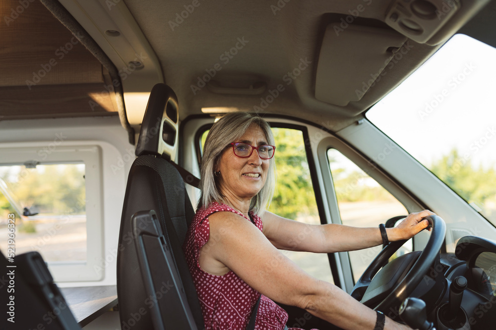 Mature woman driving camper van on road trip Mature woman driving camper van on road trip
