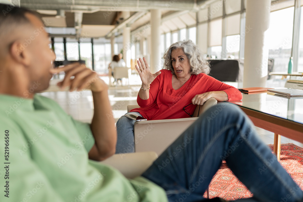 Senior businesswoman discussing ideas with colleague sitting in office Senior businesswoman discussing ideas with colleague sitting in office