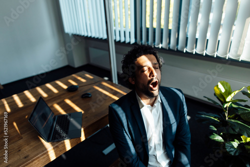 Tired businessman yawning at workplace photo