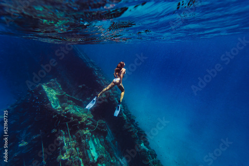 Woman swimming underwater by shipwreck in sea photo