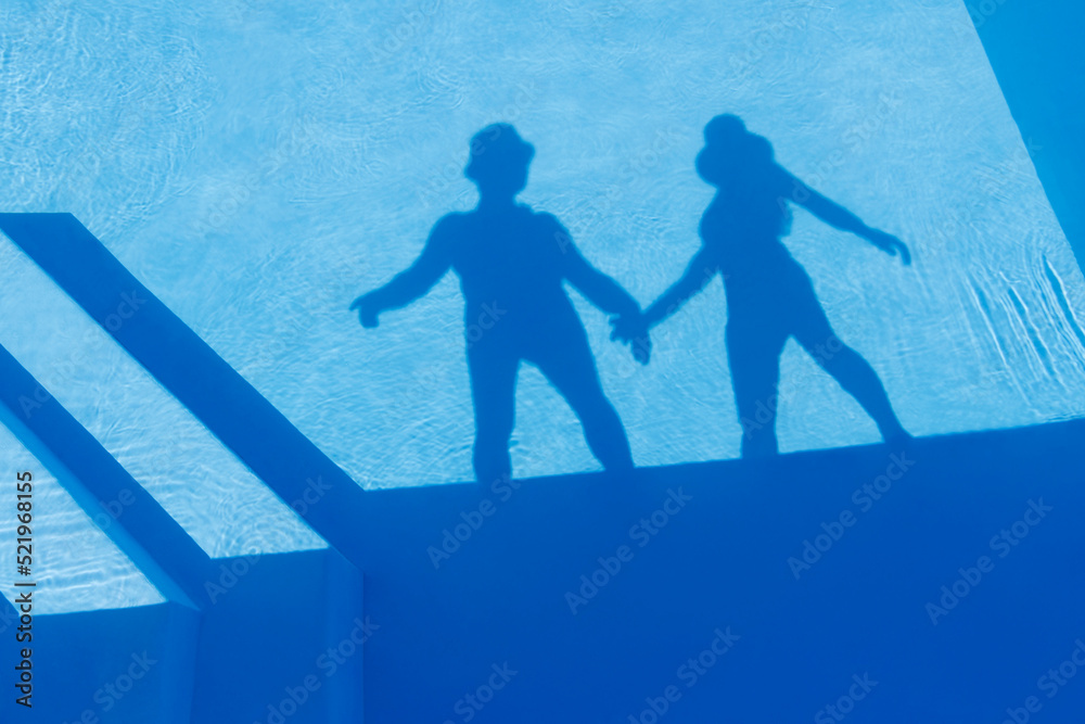 Shadow of couple holding hands seen on water of swimming pool Shadow of couple holding hands seen on water of swimming pool