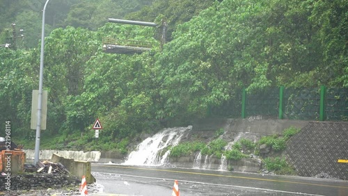 Dangerous driving condition with heavy rainfall that developed a little falls on the roadside at Hsuehshan Tunnel at Hualien City, Taiwan, during bad weather condition with typhoon approaching. photo