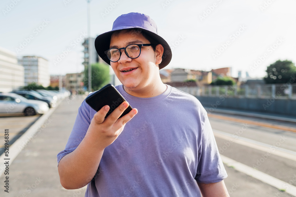 Teenage boy talking on speaker of smart phone on street Teenage boy talking on speaker of smart phone on street