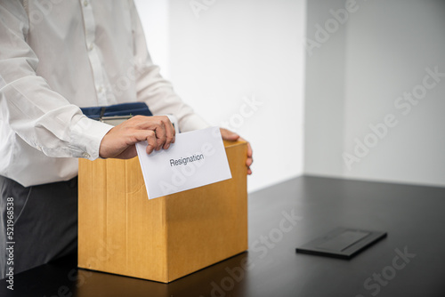 Business man sending resignation letter and packing Stuff Resign Depress or carrying business cardboard box by desk in office. Change of job or fired from company