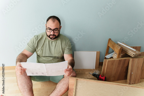 Man reading instruction manual sitting on floor at home photo
