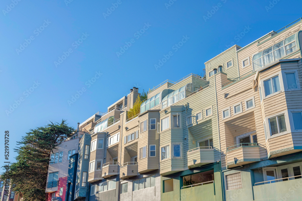 Low angle view of townhouses with wood lap siding and garden roof on roof deck