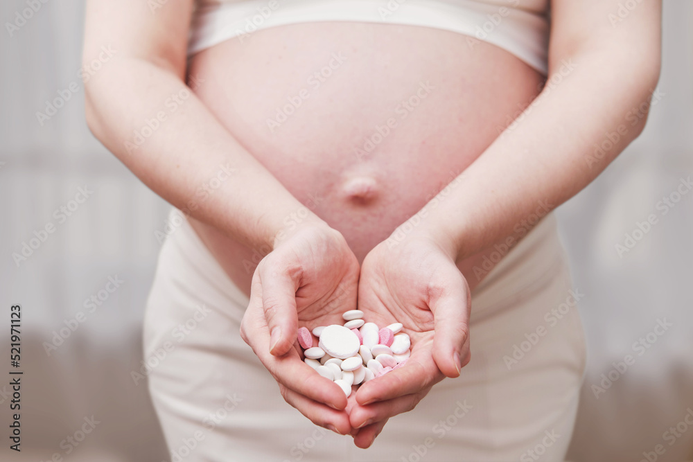 Pills in the hands of a pregnant woman, home living room Pills in the hands of a pregnant woman, home living room