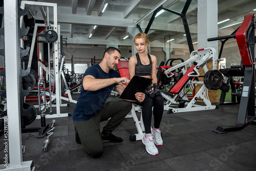Beautiful young couple of man and woman are training in the gym to keep fit.