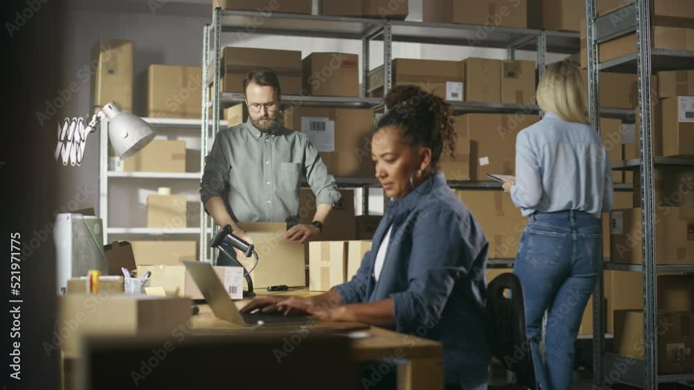 Multicultural Team of Warehouse Employees at Work in Retail Shop's Storeroom. Small Business Owners and Inventory Managers Working on Laptop, Tablet, Packing Parcels for Delivery. Multicultural Team of Warehouse Employees at Work in Retail Shop's Storeroom. Small Business Owners and Inventory Managers Working on Laptop, Tablet, Packing Parcels for Delivery.