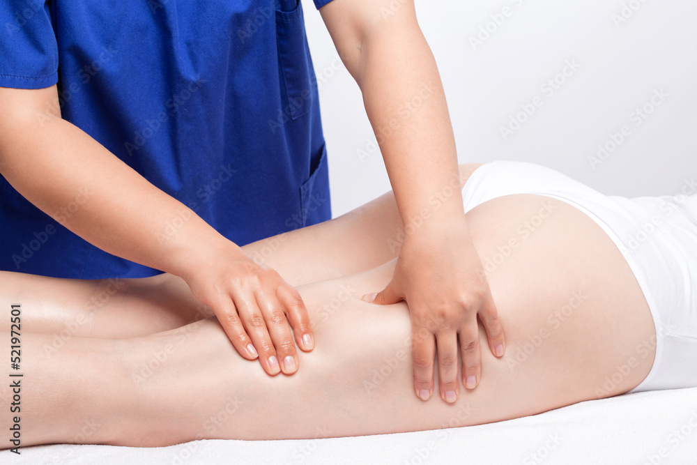 Fototapeta premium Masseur makes anti-cellulite massageon the legs, thighs, hips and buttocks in the spa. Overweight treatment, body sculpting.Cosmetology and massage concept.