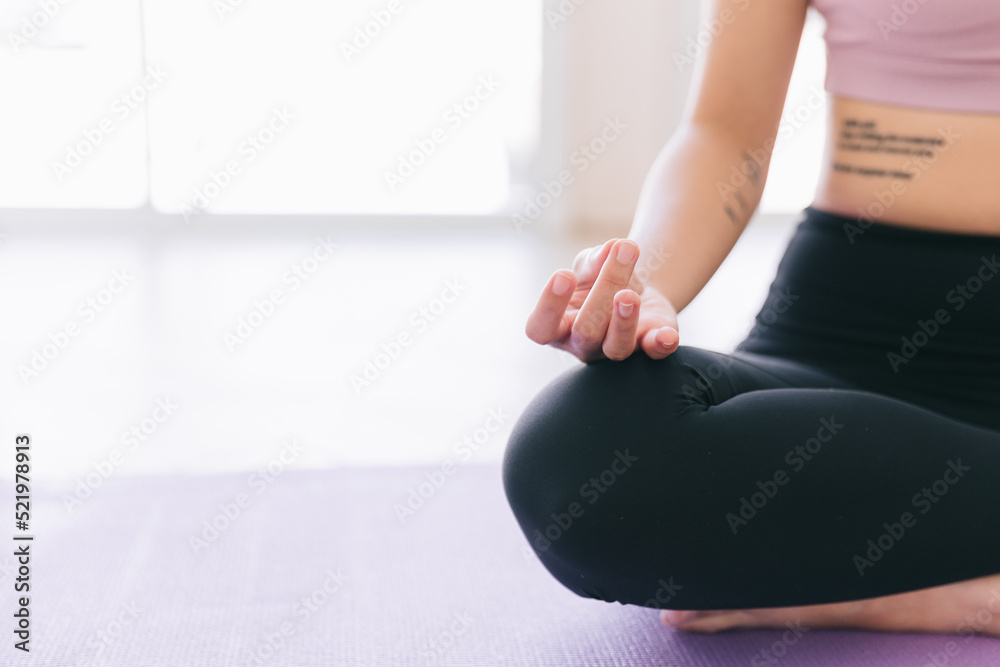 Close up of meditation hand of sporty Asian woman practicing yoga on yoga mat, doing Ardha Padmasana exercise, meditating in Half Lotus pose, indoor working out at home.