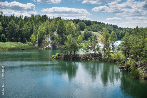 A rocky, tree-covered island in a blue-green lake where there was a granite quarry