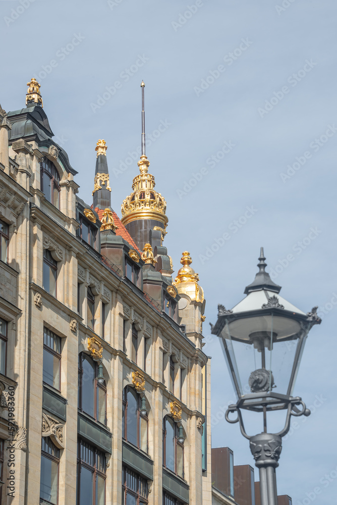 Street lamp, red roofs and golden towers. Cityscape of historical downtown in Leipzig at blue sky and sunny day, Germany.