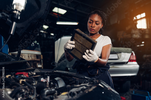 Woman auto mechanic checking air filter and repair maintenance auto engine is problems at car repair shop. © kelvn
