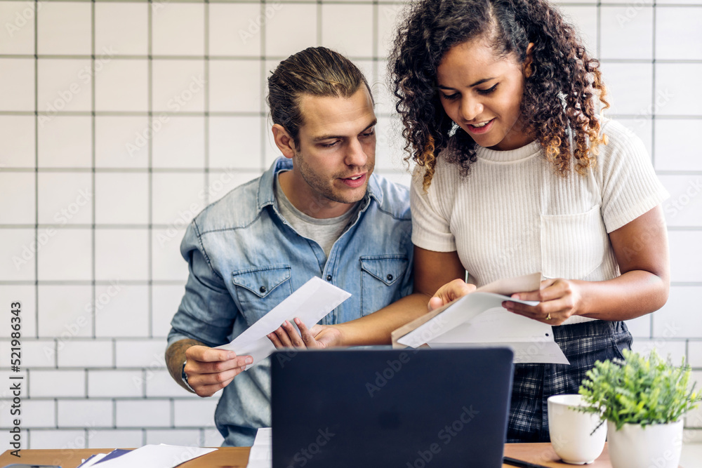 Obraz premium Happy couple use laptop computer reading documents and calculating bills to pay together.business couple hold paper bills managing account invoice at home.loan bankruptcy money concept
