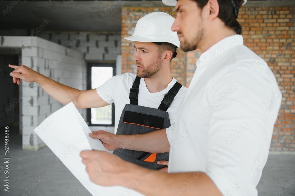 Male Architect Giving Instructions To His Foreman At Construction Site. Male Architect Giving Instructions To His Foreman At Construction Site.