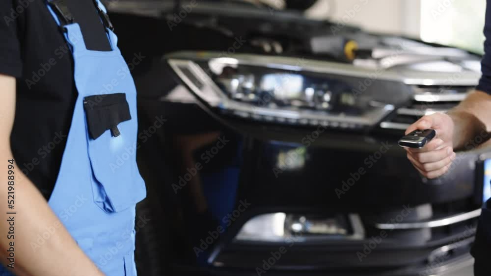 Close up shot of hands of mechanic giving car key to male client after servicing in auto repair shop. Car repair. Vehicle breaks down Close up shot of hands of mechanic giving car key to male client after servicing in auto repair shop. Car repair. Vehicle breaks down