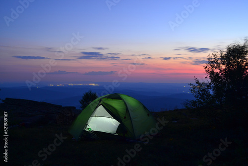 Tent on top of the mountain. Night landscape. Sunset. Bird's eye view, city and mountains.