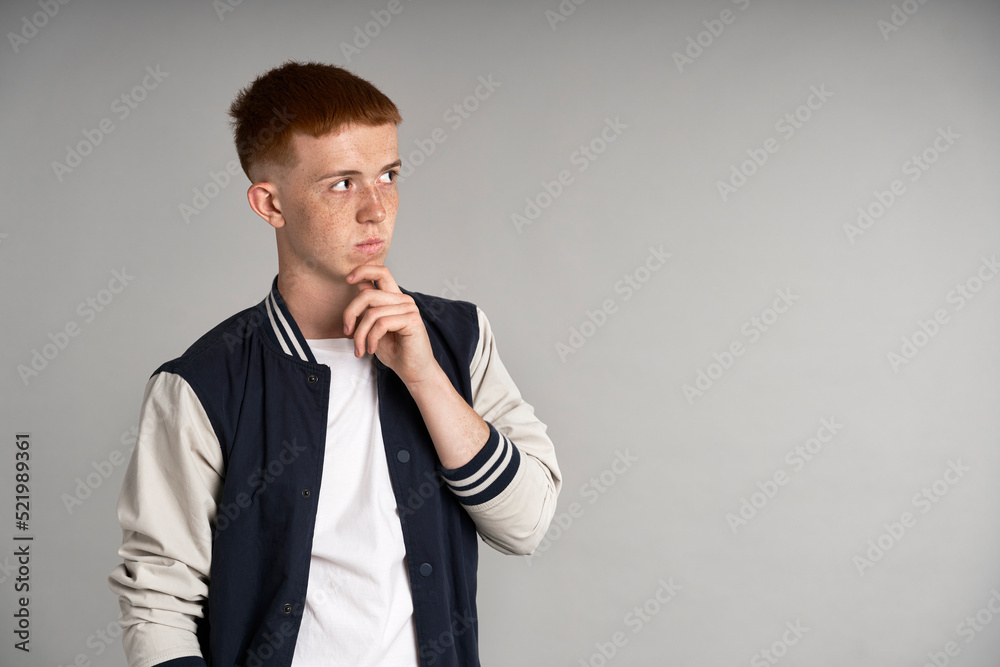 Young ginger male student thinking about something and looking at copy space Young ginger male student thinking about something and looking at copy space