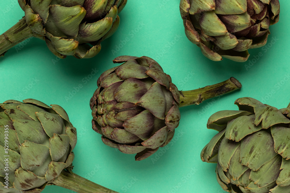 Obraz premium Big fresh artichokes on green background. Top view.