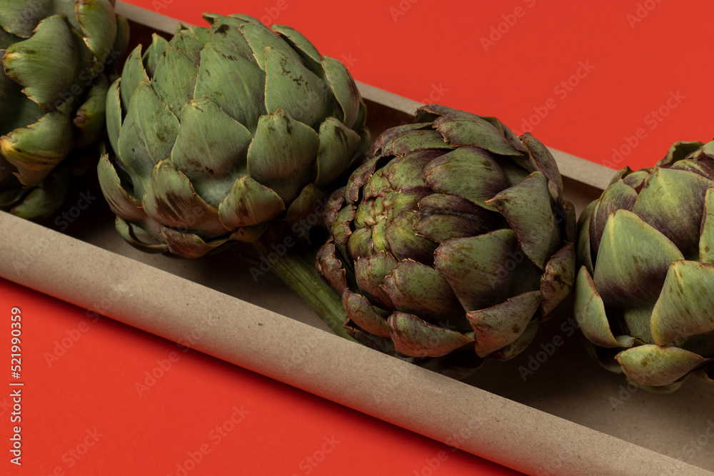 Fototapeta premium Big fresh green artichokes on a red background.