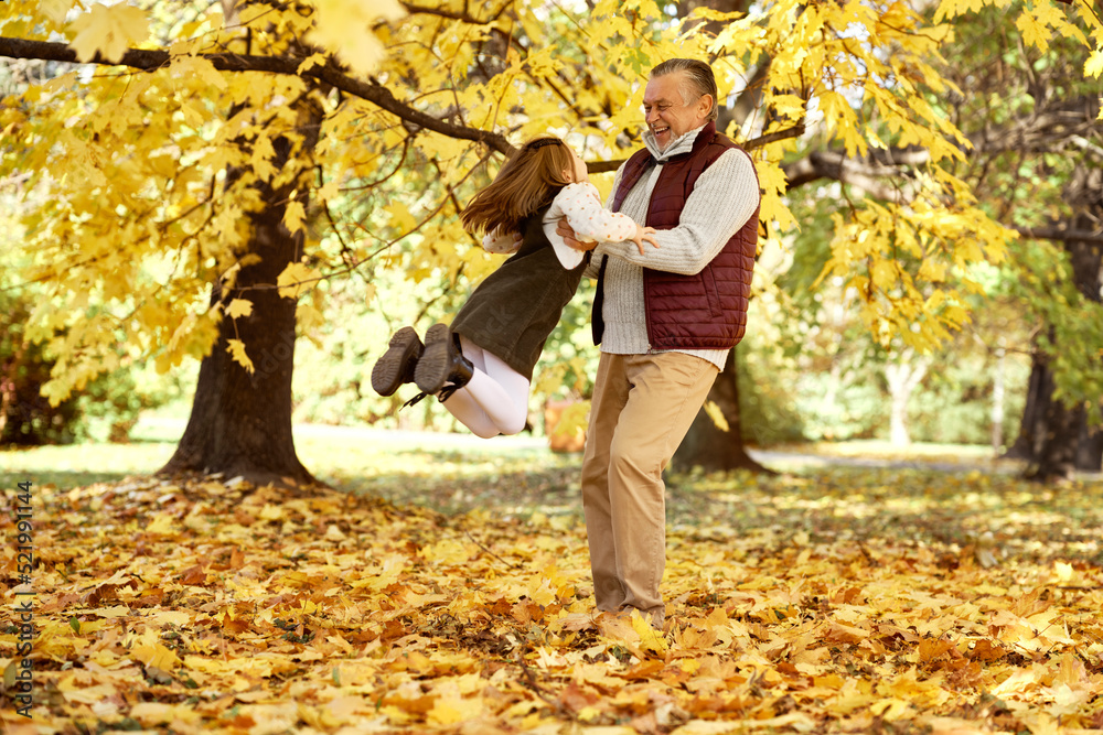 Senior man with her granddaughter have fun at the park in autumn Senior man with her granddaughter have fun at the park in autumn