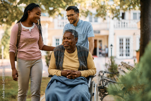 Happy black woman visiting her senior father in nursing home.