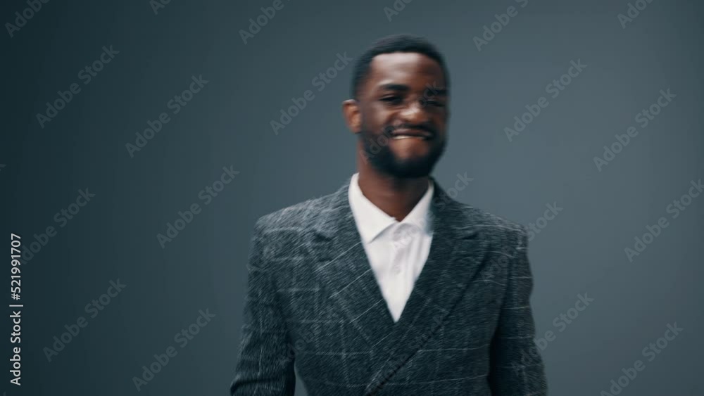 An African-American businessman man dancing to the music in his head in his office against a dark background in a business suit and happy Friday, days off and time off from work An African-American businessman man dancing to the music in his head in his office against a dark background in a business suit and happy Friday, days off and time off from work
