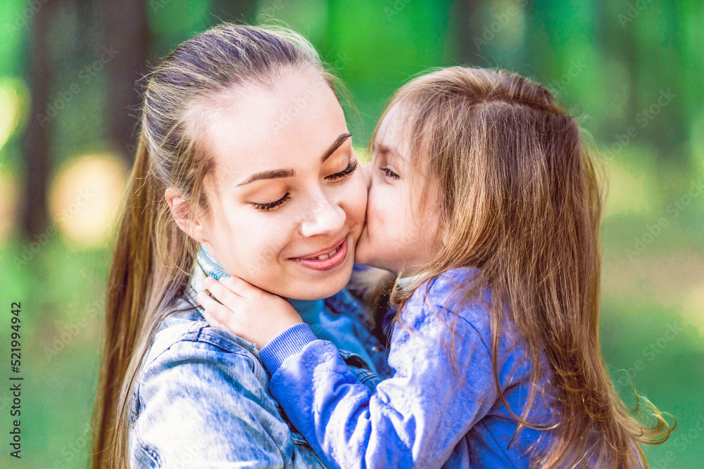 Daughter in the arms of my mother, kisses, hugs. Tenderness, love. On the background of trees, close-up Daughter in the arms of my mother, kisses, hugs. Tenderness, love. On the background of trees, close-up