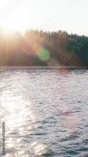 vertical video of sunlight on trees and river with waves
