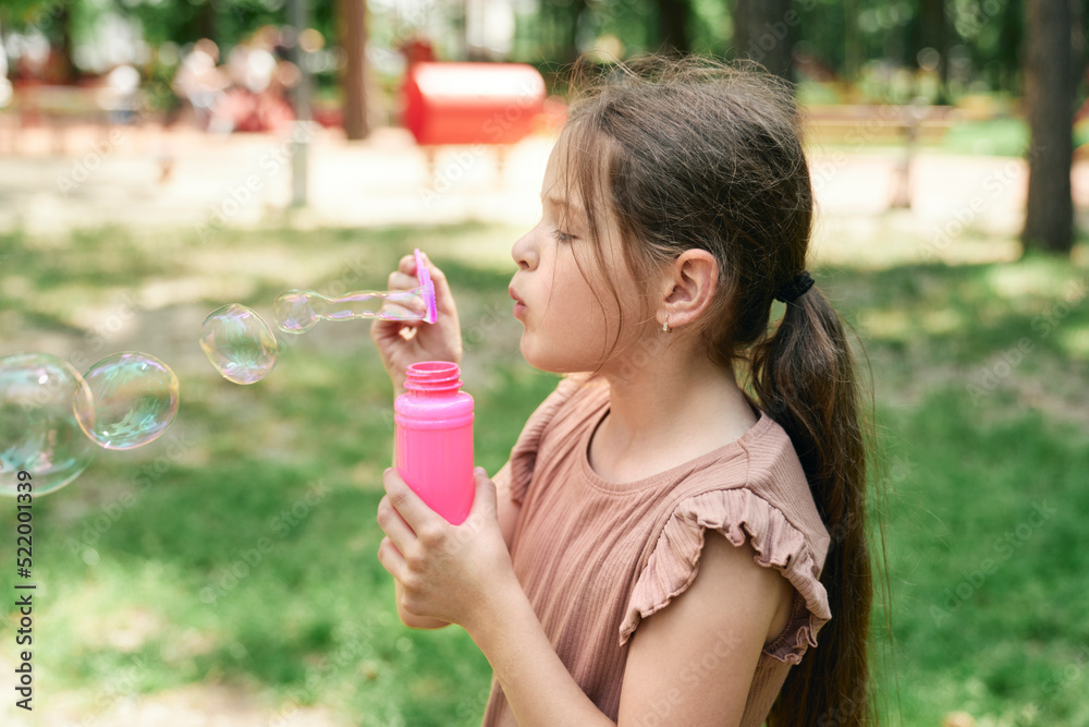 Caucasian girl blowing soap bubbles at the park