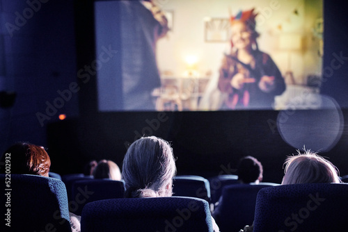 Rear view shot of unrecognizable people spending spare time watching family movie on big screen at cinema photo
