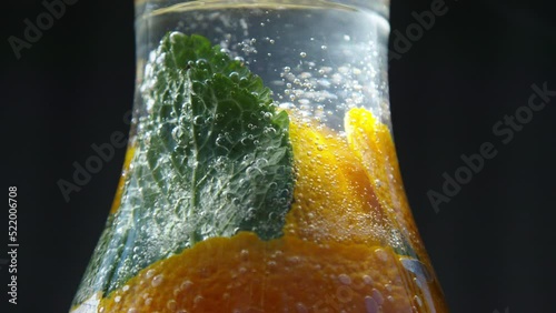 Sparkling water jug with orangle peel and mint leafs. Close up. photo