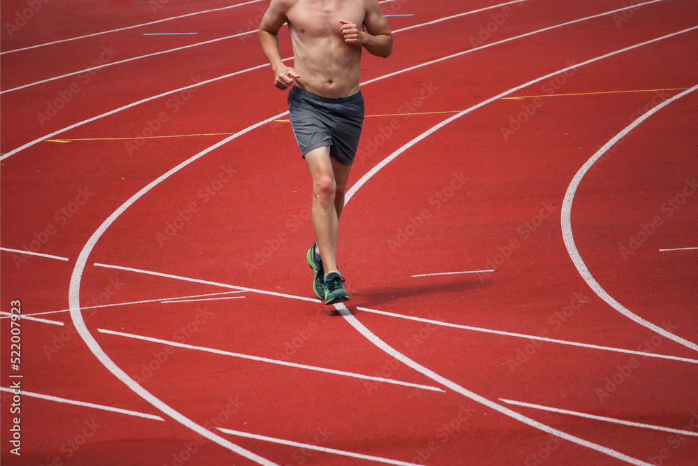 Obraz premium Rear view of an male athlete starting his sprint on an stadium running track