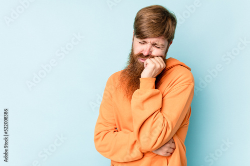 Young caucasian red-haired man isolated on blue background who feels sad and pensive, looking at copy space.