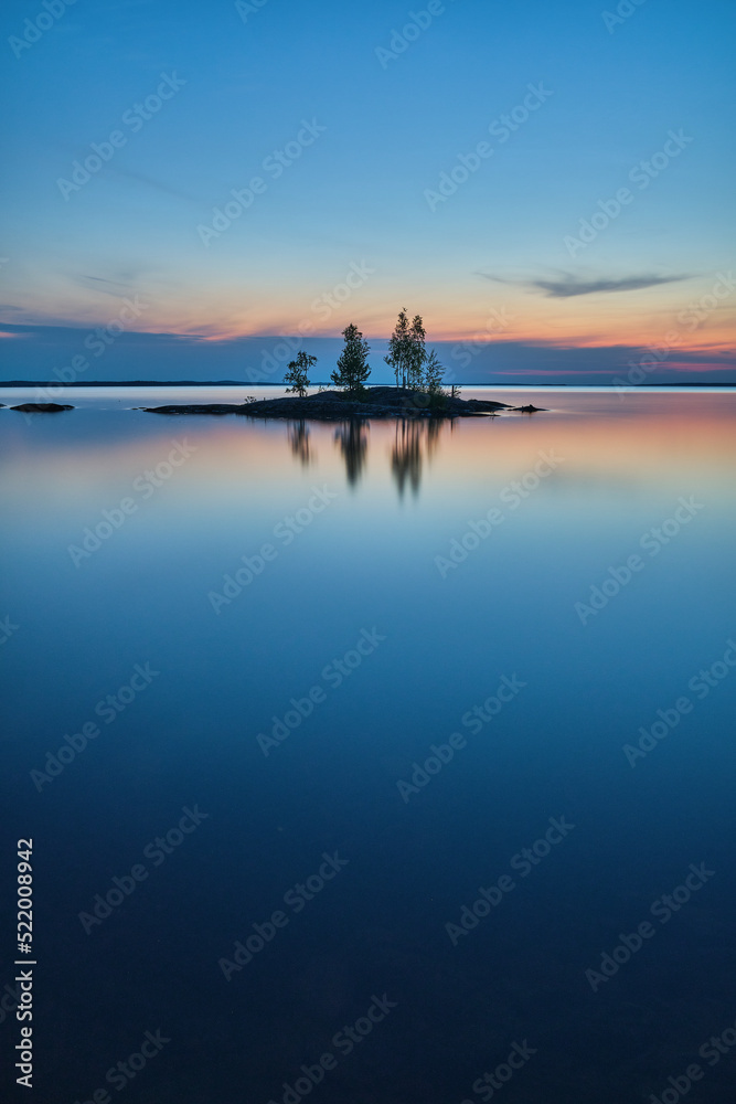 Small island in dusk surrounded by water at night