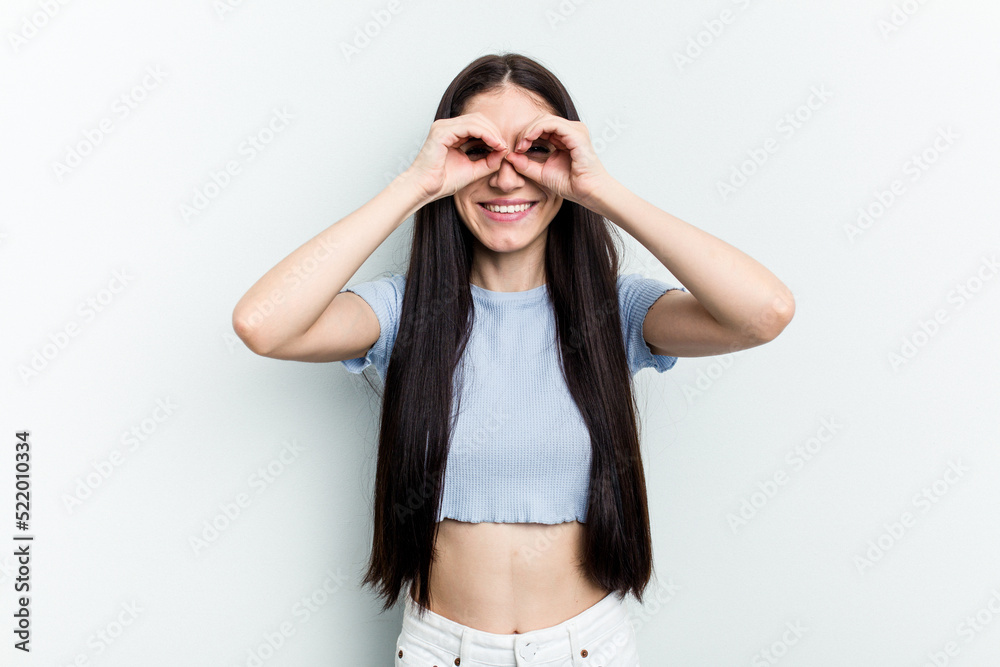 Young caucasian woman isolated on white background showing okay sign over eyes Young caucasian woman isolated on white background showing okay sign over eyes