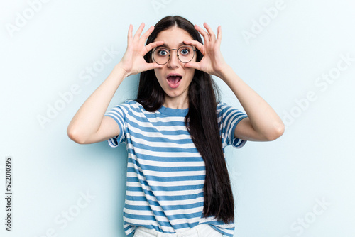 Young caucasian woman isolated on blue background keeping eyes opened to find a success opportunity.